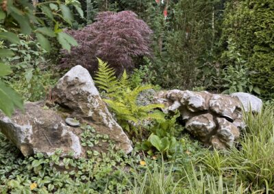 Přírodní mramorové solitéry DODODOS v okrasném zahradním záhonu s japonským javorem.